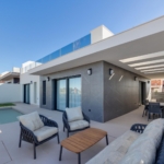 Modern backyard patio with a rectangular pool, white walls, and outdoor seating under a covered area on a sunny day calm and inviting.
