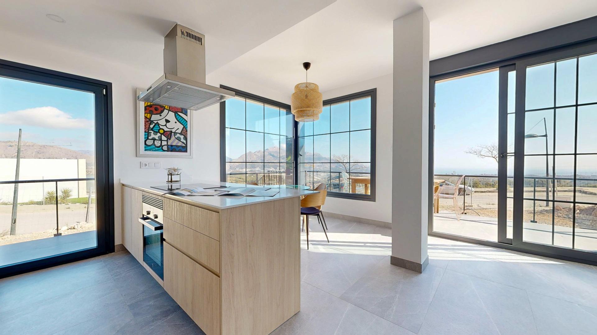 Modern kitchen island with a stainless range hood and large grid windows showing mountains outside outside.