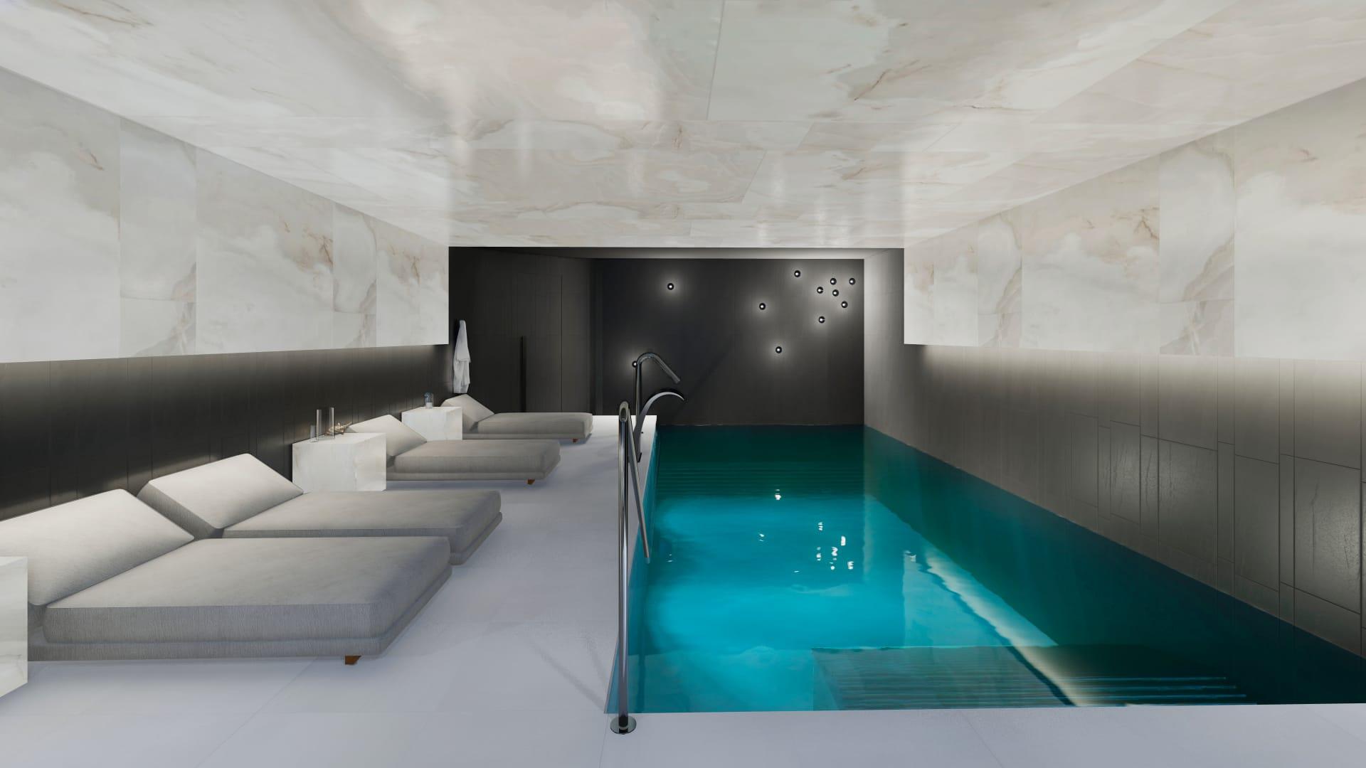 Indoor spa pool area with turquoise water, white marble walls/ceiling, and a row of gray lounge chairs along the left side.