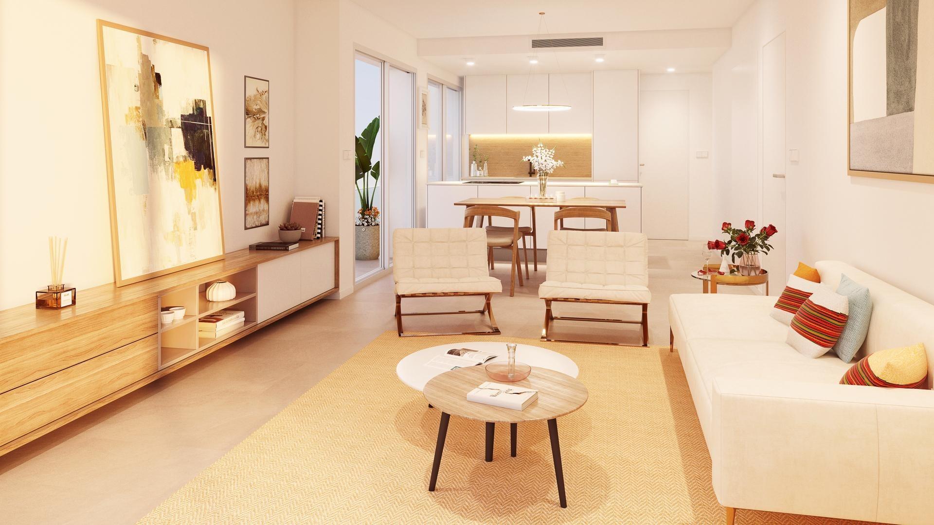 Open-concept living room with a white sofa, two cream chairs, and wooden coffee tables; kitchen visible in the background.