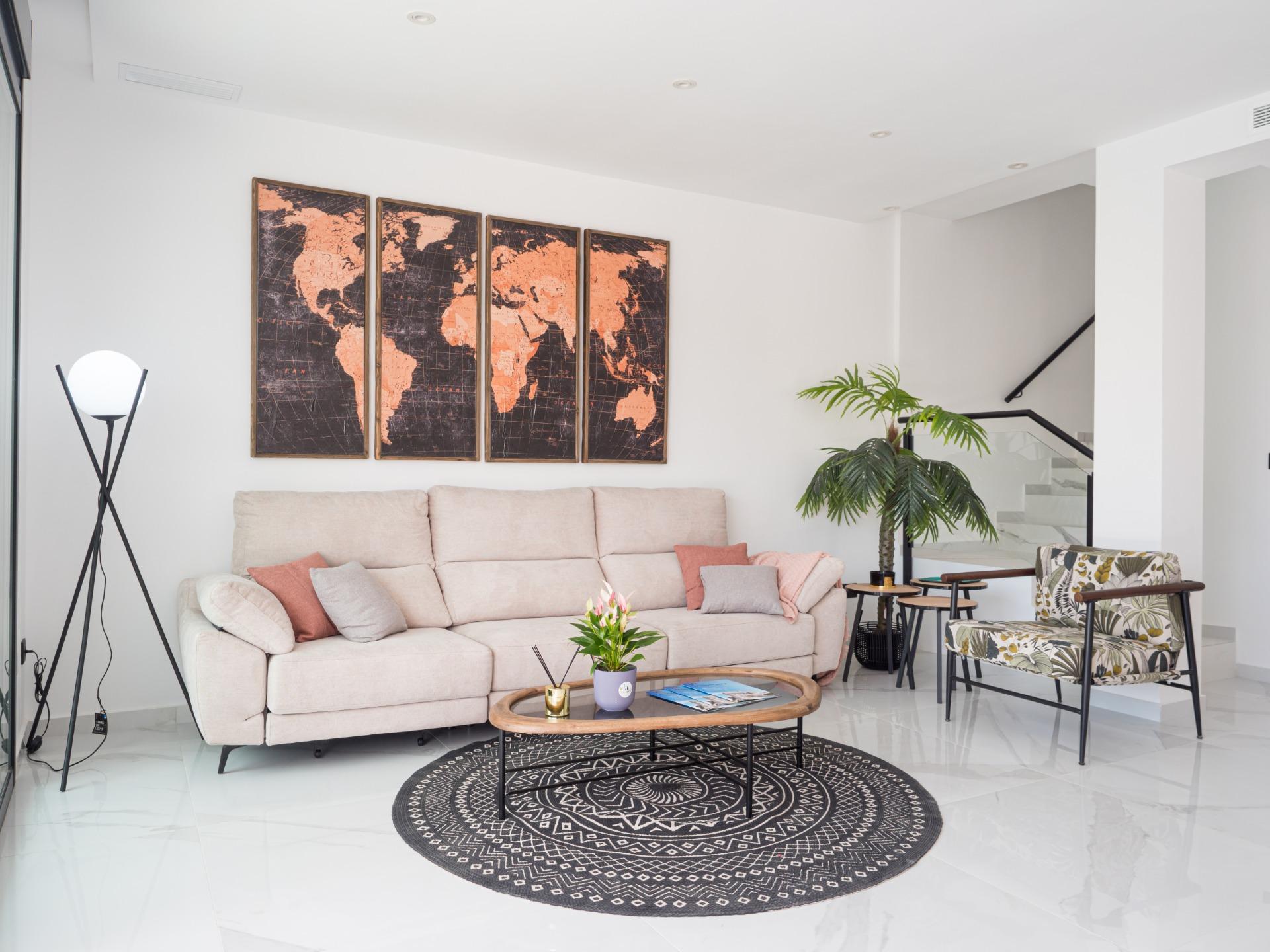 Living room with a beige sectional, four-panel world map art, and a black circular rug in the center.