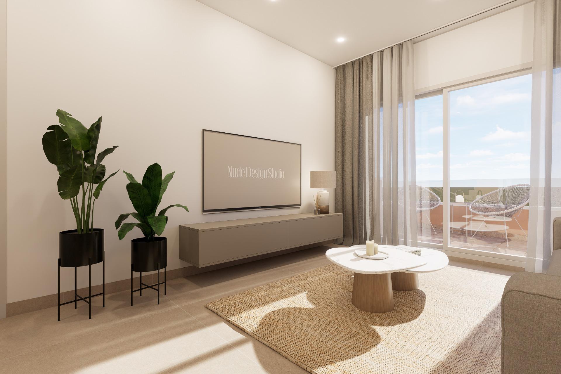 Minimalist living room: wall TV over a beige console, two tall potted plants, and sheer curtains by a sliding glass door to a balcony.