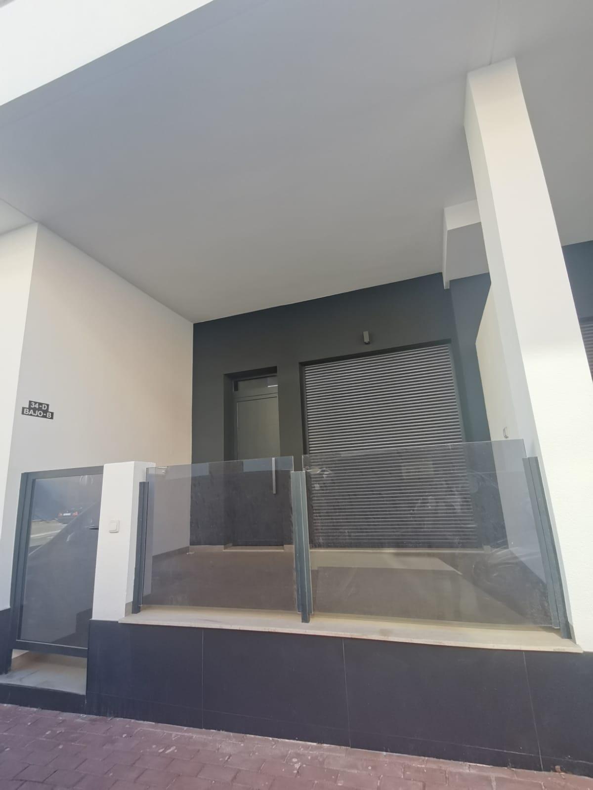 Modern building entrance with glass railing, dark gray walls, and a metal roll-up door.