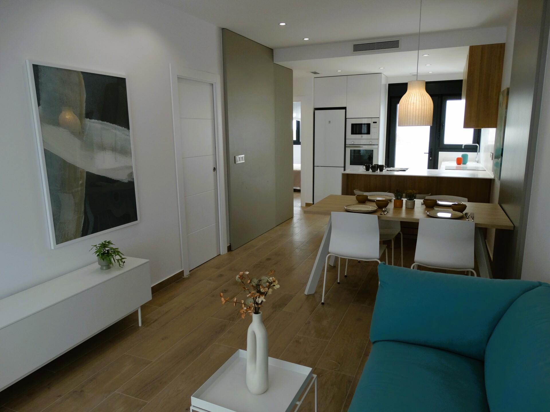 Open-plan living and dining area with a teal couch, white coffee table, and a wooden dining table.