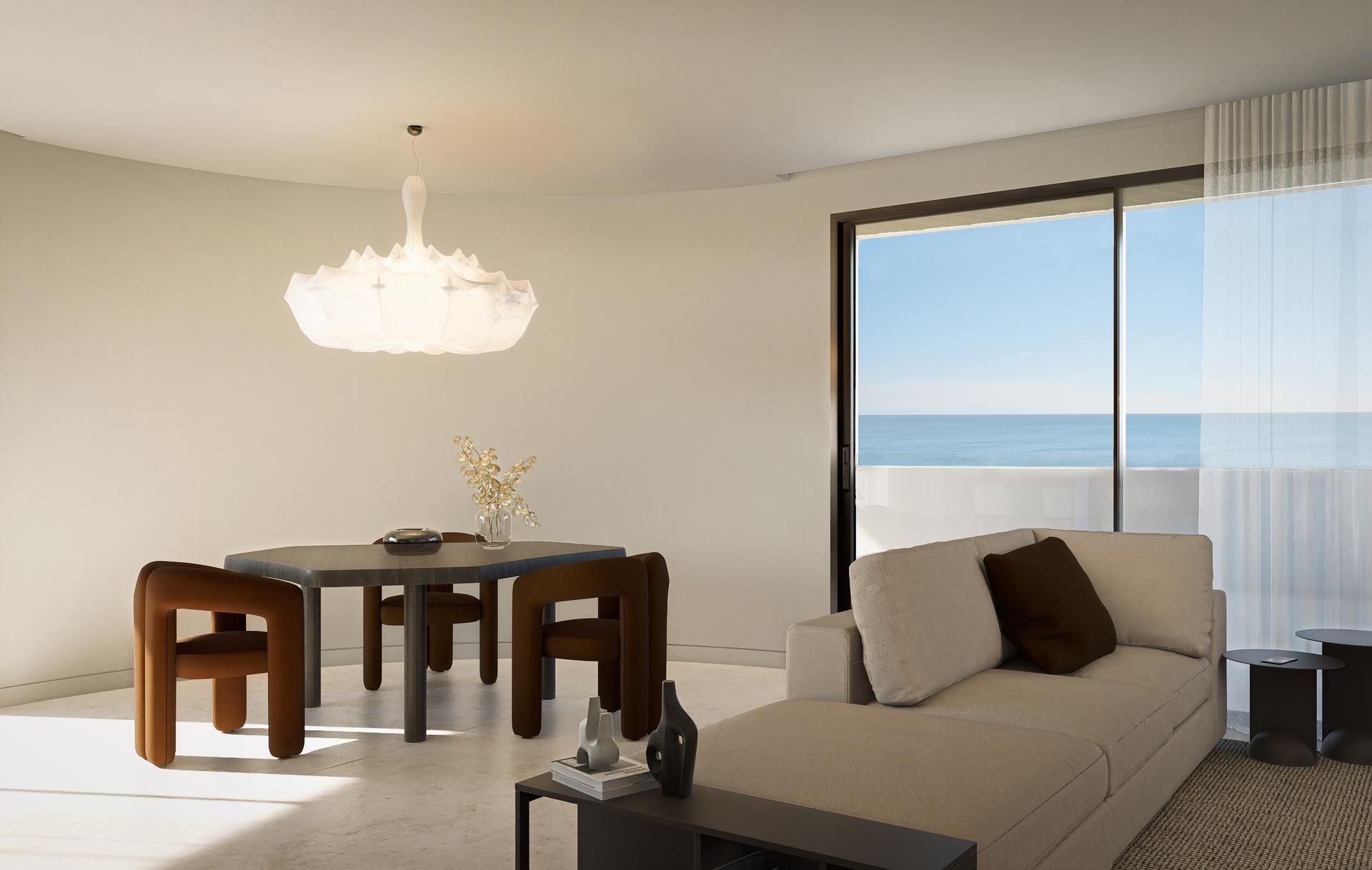 Modern living and dining area with a large window showing the ocean; beige sofa and dark wood table with brown chairs.