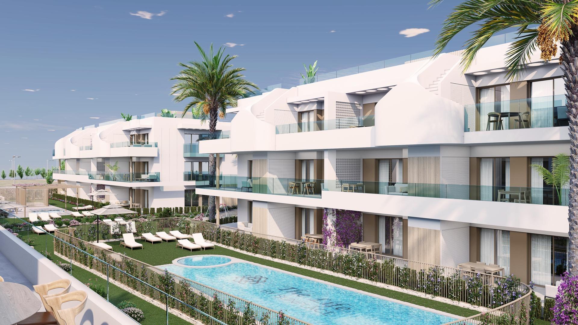 Modern white apartment complex with glass balconies surrounding a central pool and palm trees in a sunny setting.