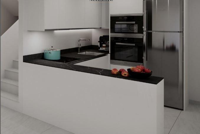 Modern white kitchen with a black countertop island, sink, and stainless steel fridge with built-in double ovens.