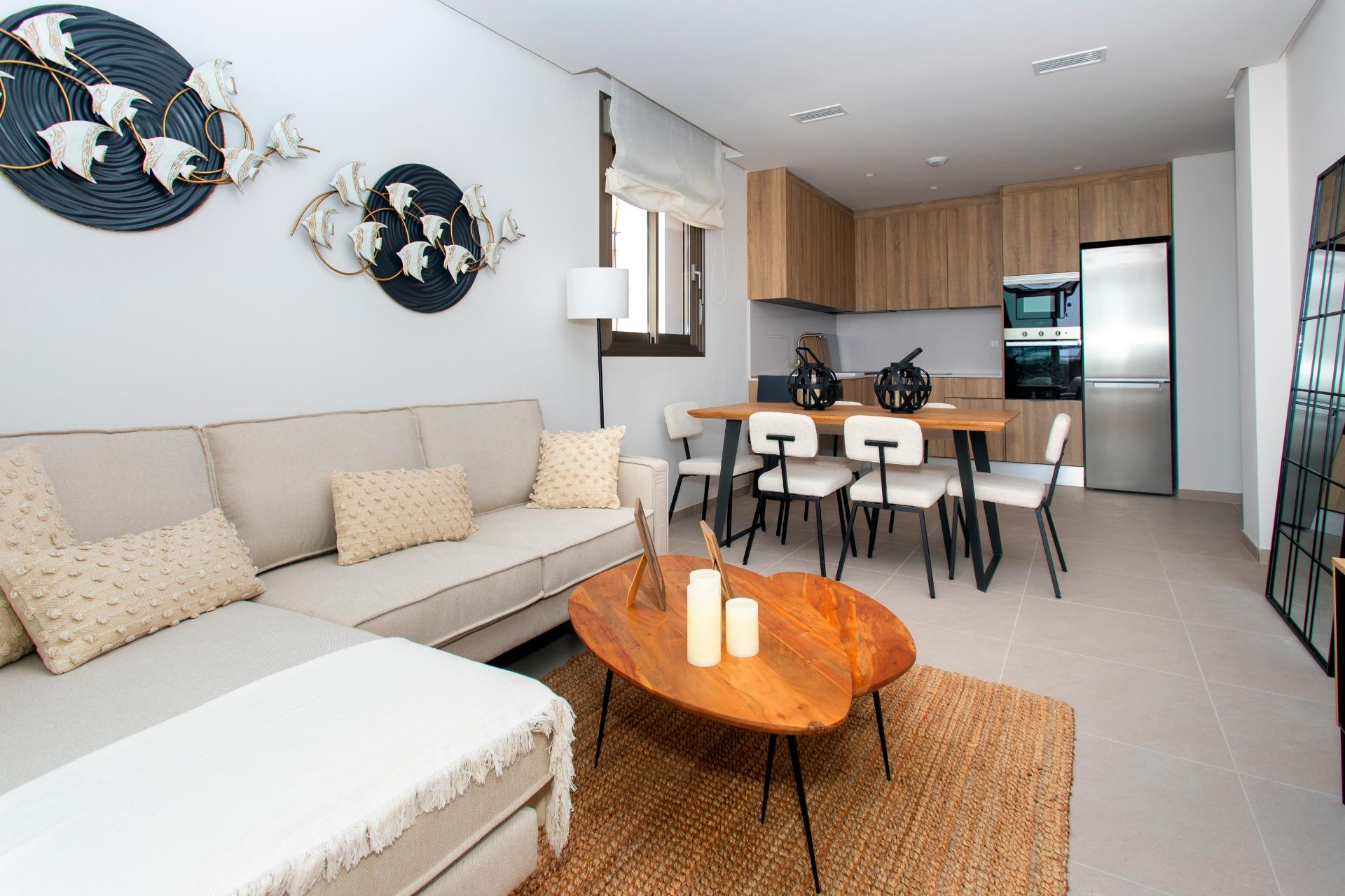 Open-plan living room and kitchen with a beige sofa, wooden dining table, and modern chairs.