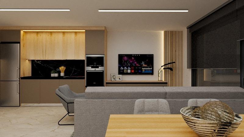 Open-plan living area with a grey sofa, wooden dining table, and a kitchen featuring light wood cabinets and a black backsplash; TV on the wall.