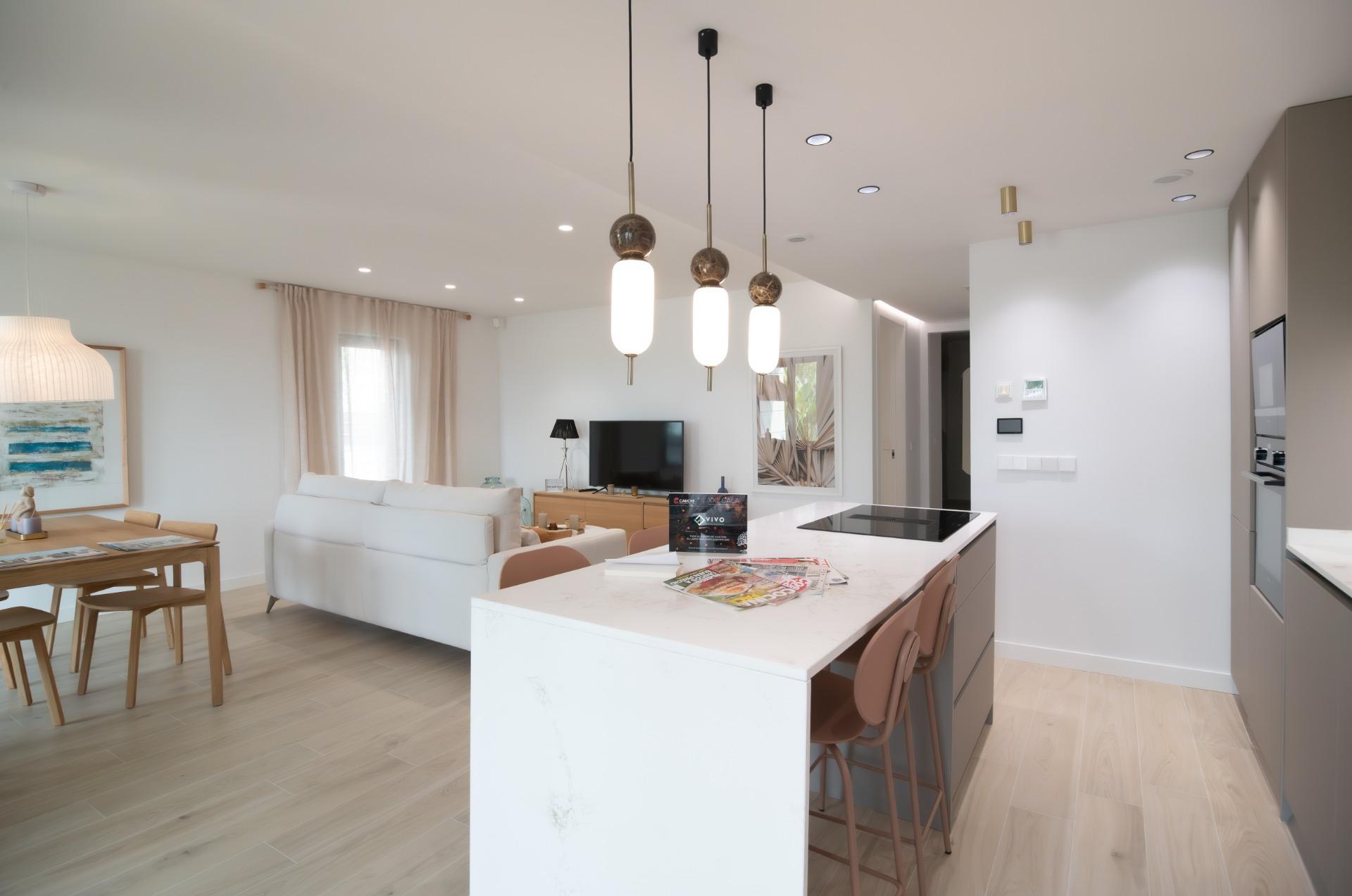 Open-plan living area with a white sofa, marble kitchen island, and three pendant lights in a bright, modern home.