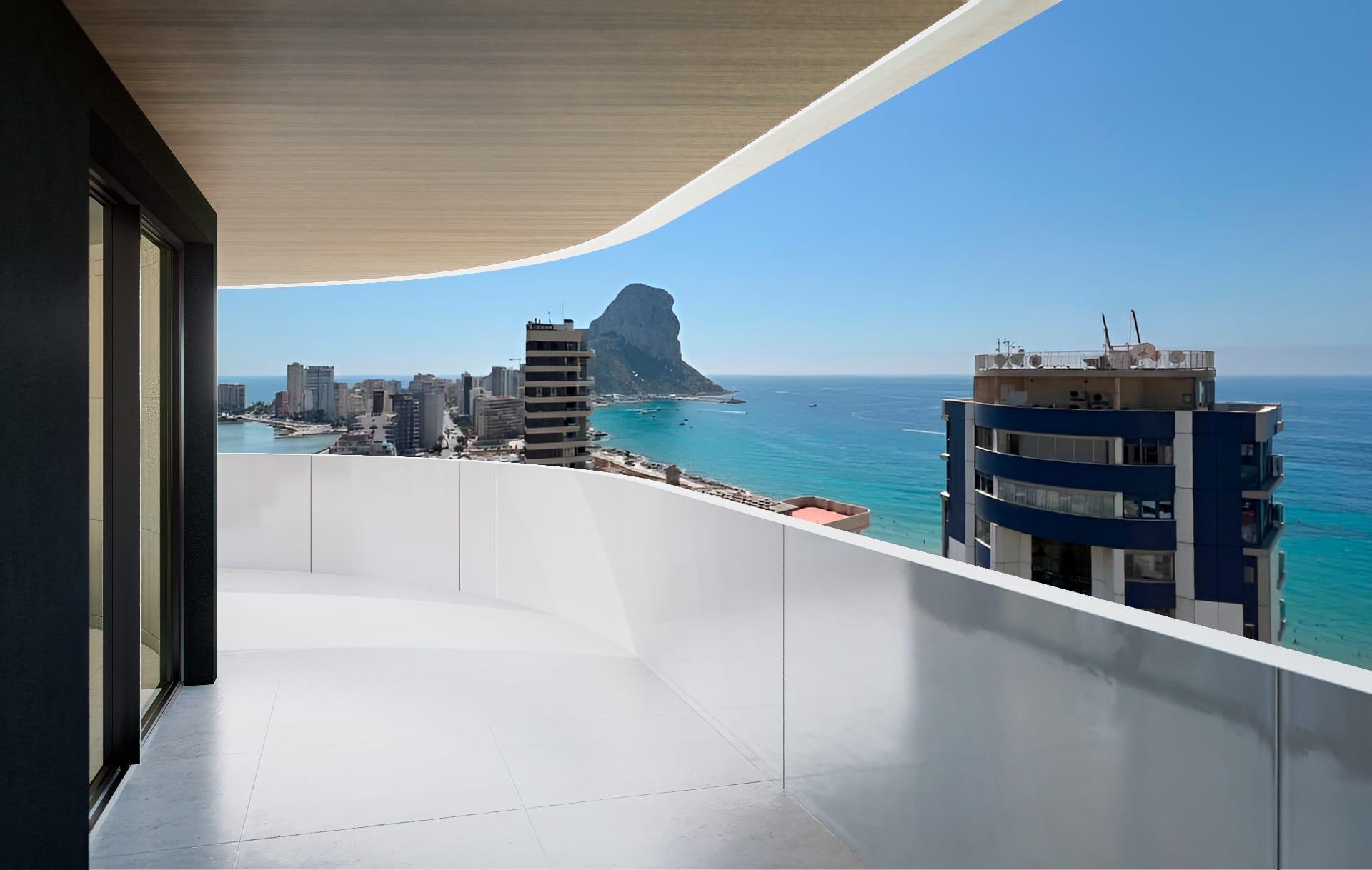Balcony with a white curved railing overlooking a coastal city and blue sea, with a rocky island in the distance.