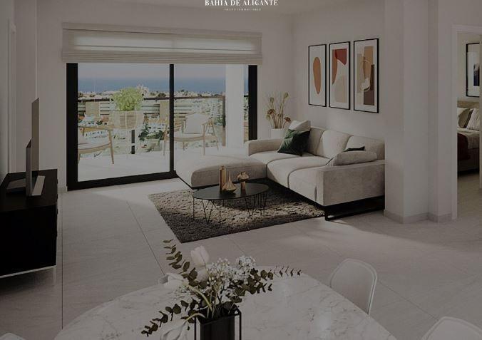 Bright modern living room with a beige sectional, glass sliding doors to a balcony, and a sea view.
