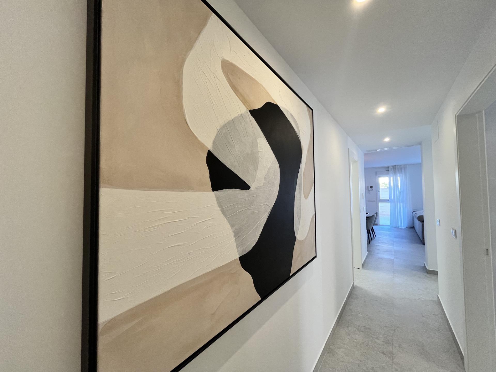 Narrow hallway with a large abstract painting on the left wall in beige, white and black tones.