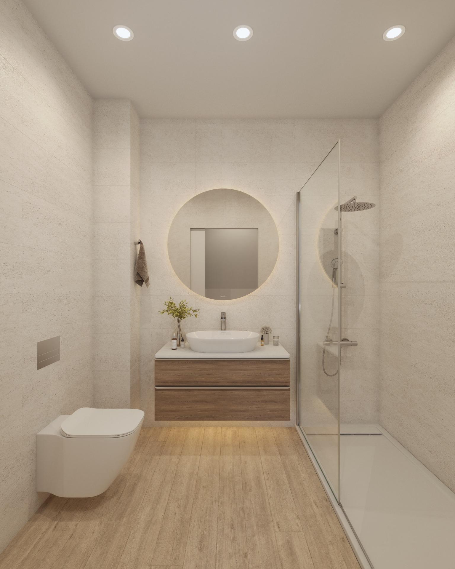 Modern bathroom with a round mirror above a wooden vanity and vessel sink, adjacent glass shower enclosure on beige tiled walls.