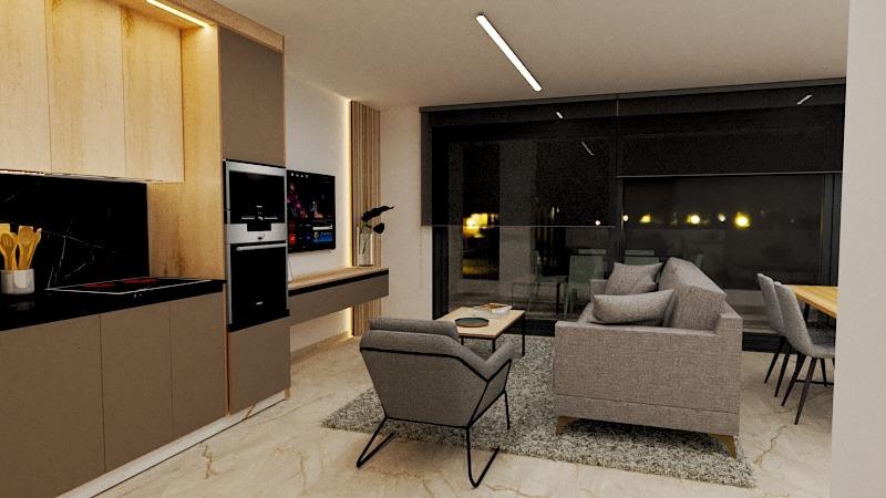 Open-plan living space with beige kitchen, built-in oven, grey sofa, lounge chair, and a glass-wall dining area at night.