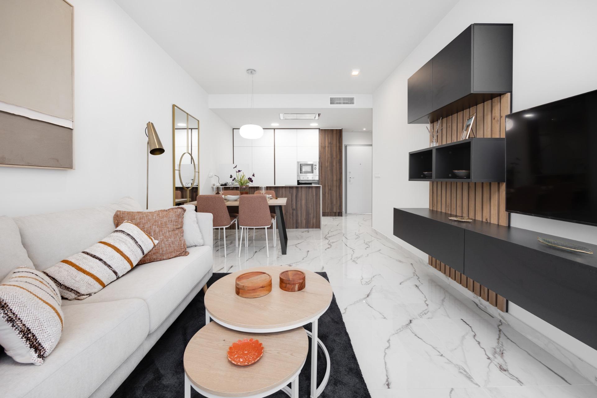 Open-plan living area with a white sofa, striped cushions, and nested round coffee tables in front of a marble floor.