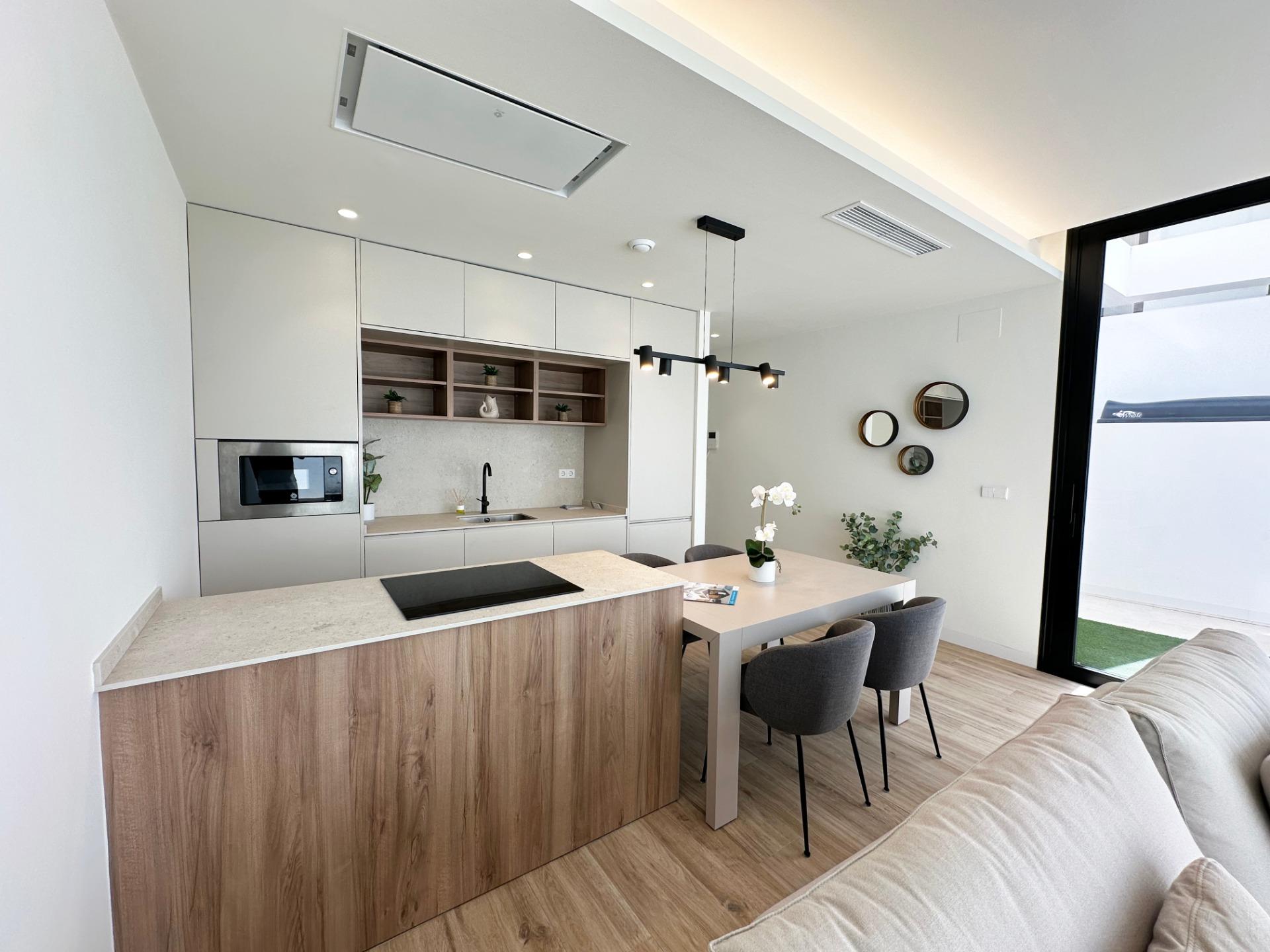 Modern open-plan kitchen and dining area with a light wood island, white cabinets, and a large glass door to the outdoors
