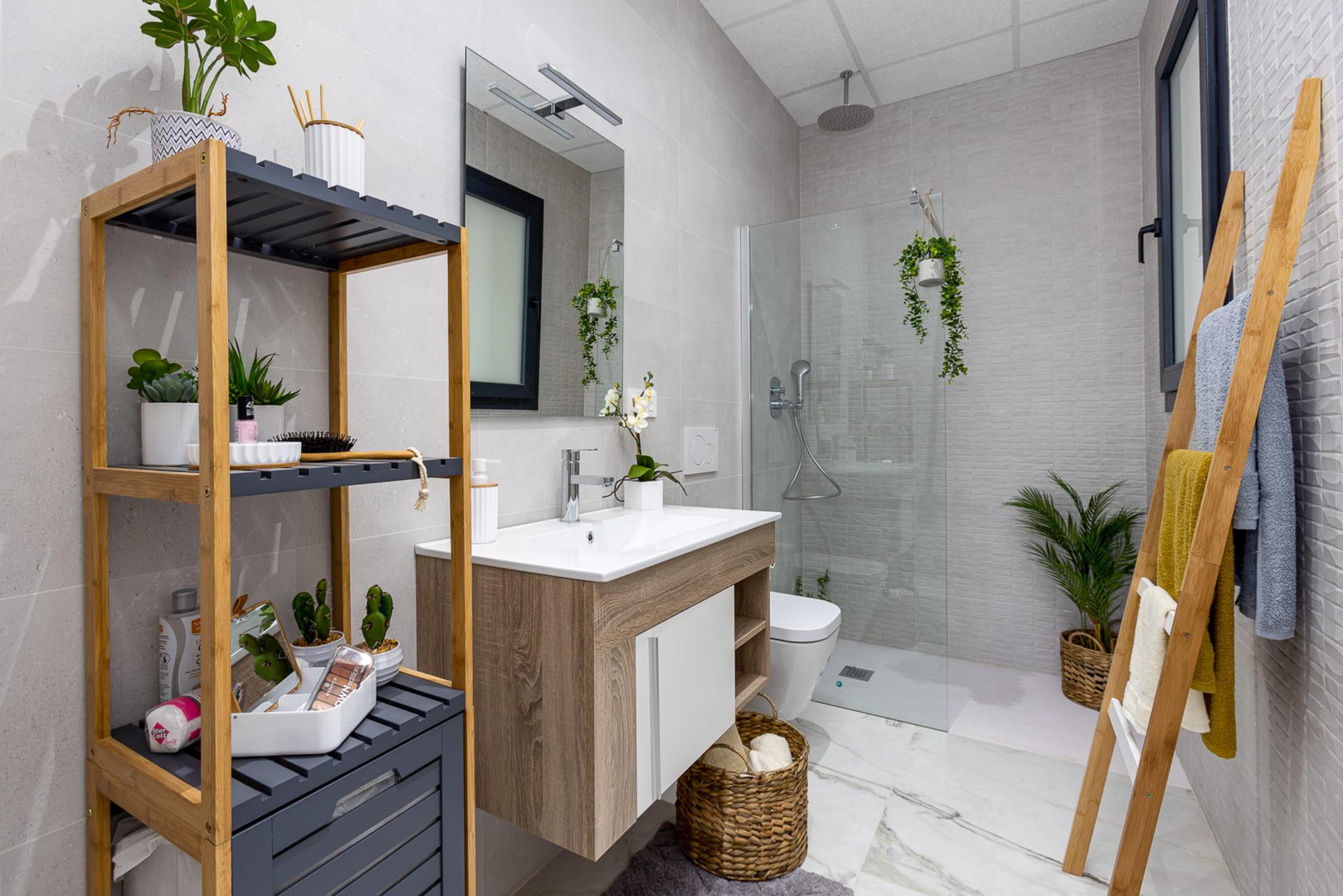 Modern bathroom with a glass-enclosed shower, floating vanity, and wooden shelving with plants.