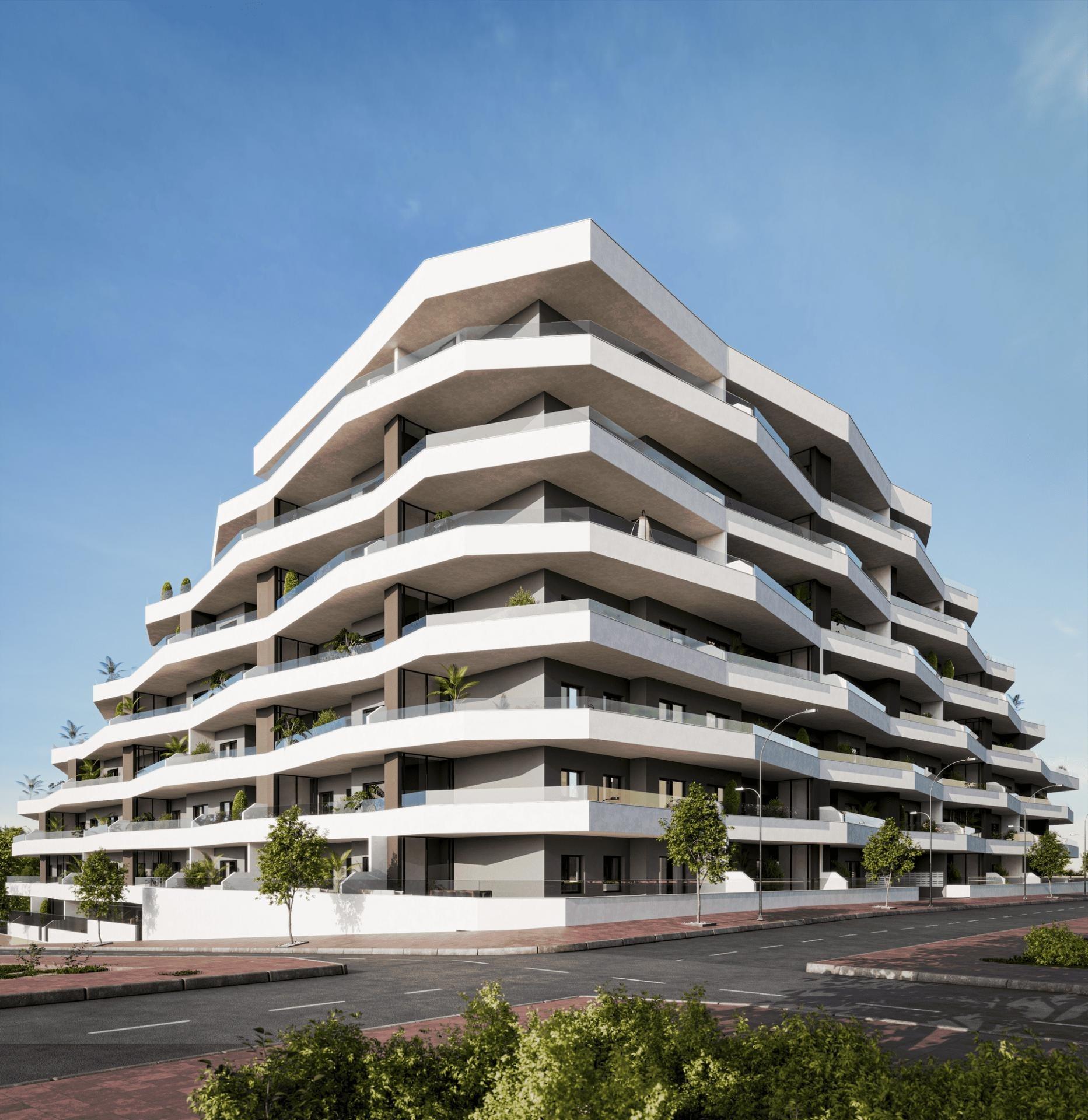 Modern white apartment building with layered curved balconies against a clear blue sky.