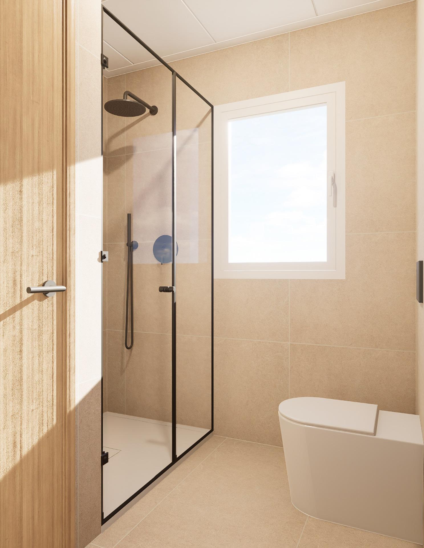 Beige tiled bathroom with a glass shower enclosure, black frame, and a round rainfall showerhead; a window provides natural light.
