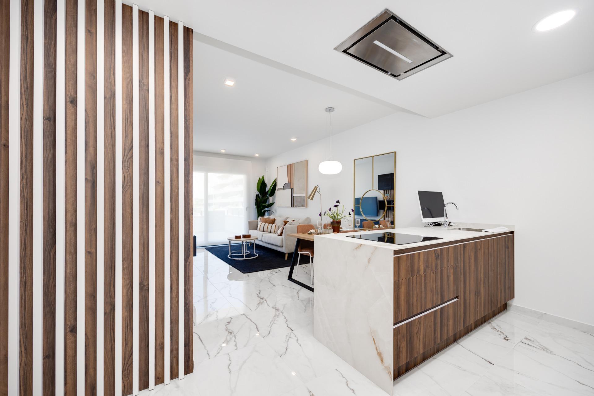 Open-concept living area with white marble floors, wood-accent kitchen island, and a slatted wooden divider on the left.