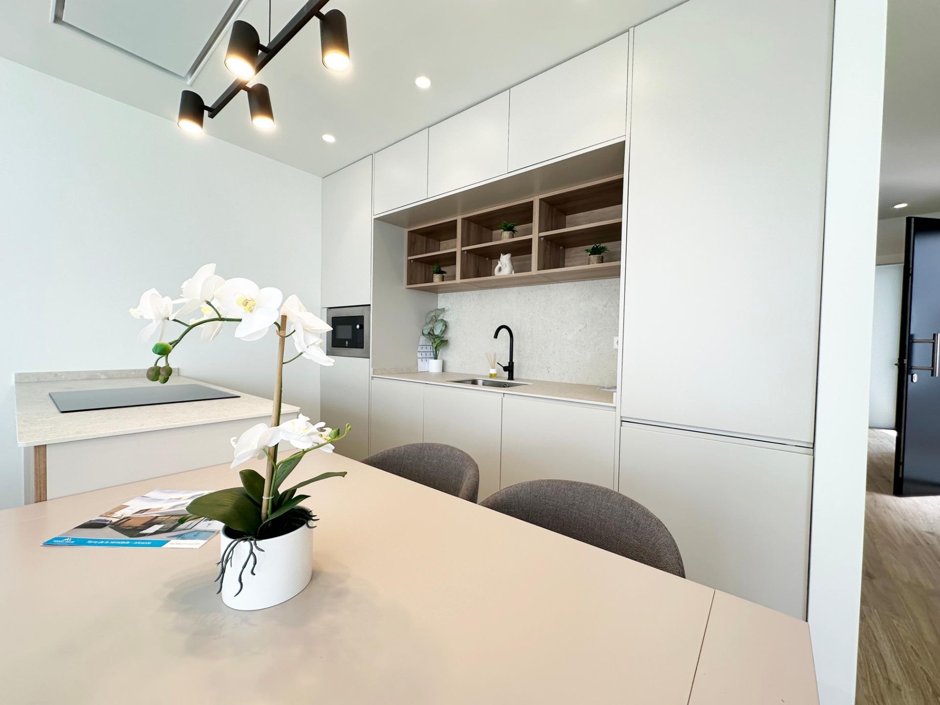 Modern white kitchen with an island, open wooden shelves, and a black faucet over a light gray countertop.