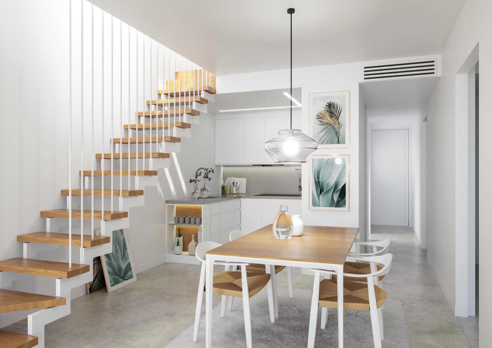Open-plan kitchen with white cabinets, wooden floating stairs on the left, and a dining table under a pendant light.