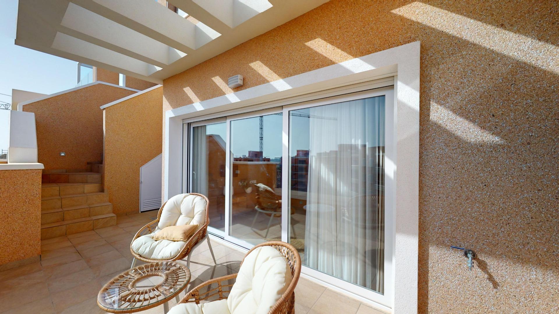 Sunny rooftop terrace with sliding glass doors, wicker chairs, and orange pebble-textured walls.