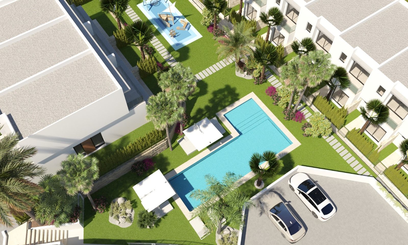 Aerial view of a modern residential complex with a rectangular pool, lounge areas, palm trees, and green courtyards between white buildings.