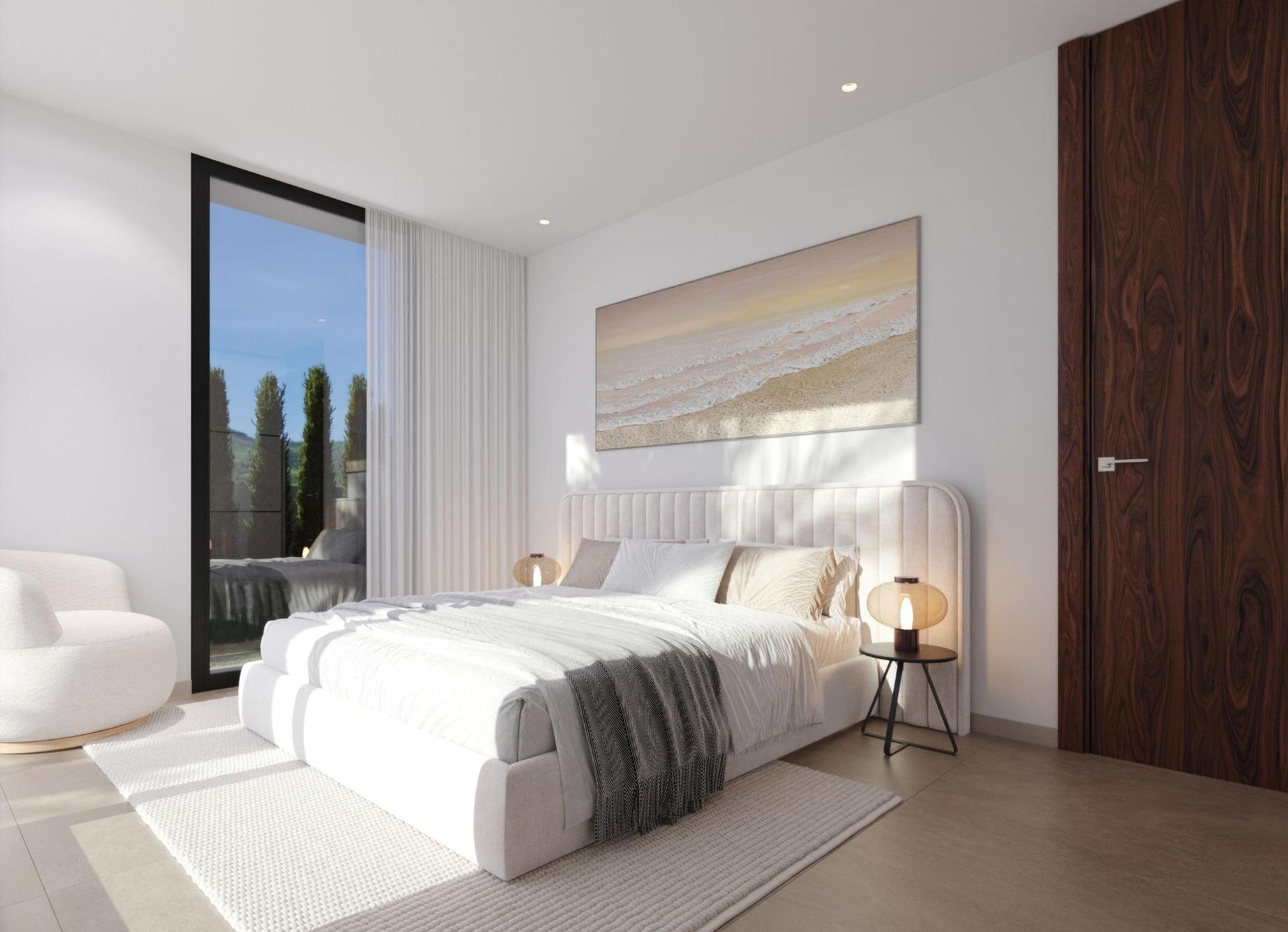 Modern bedroom with a tufted gray bed, white bedding, and two round bedside lamps on black metal tables beside a large windowed door with sheer curtains.