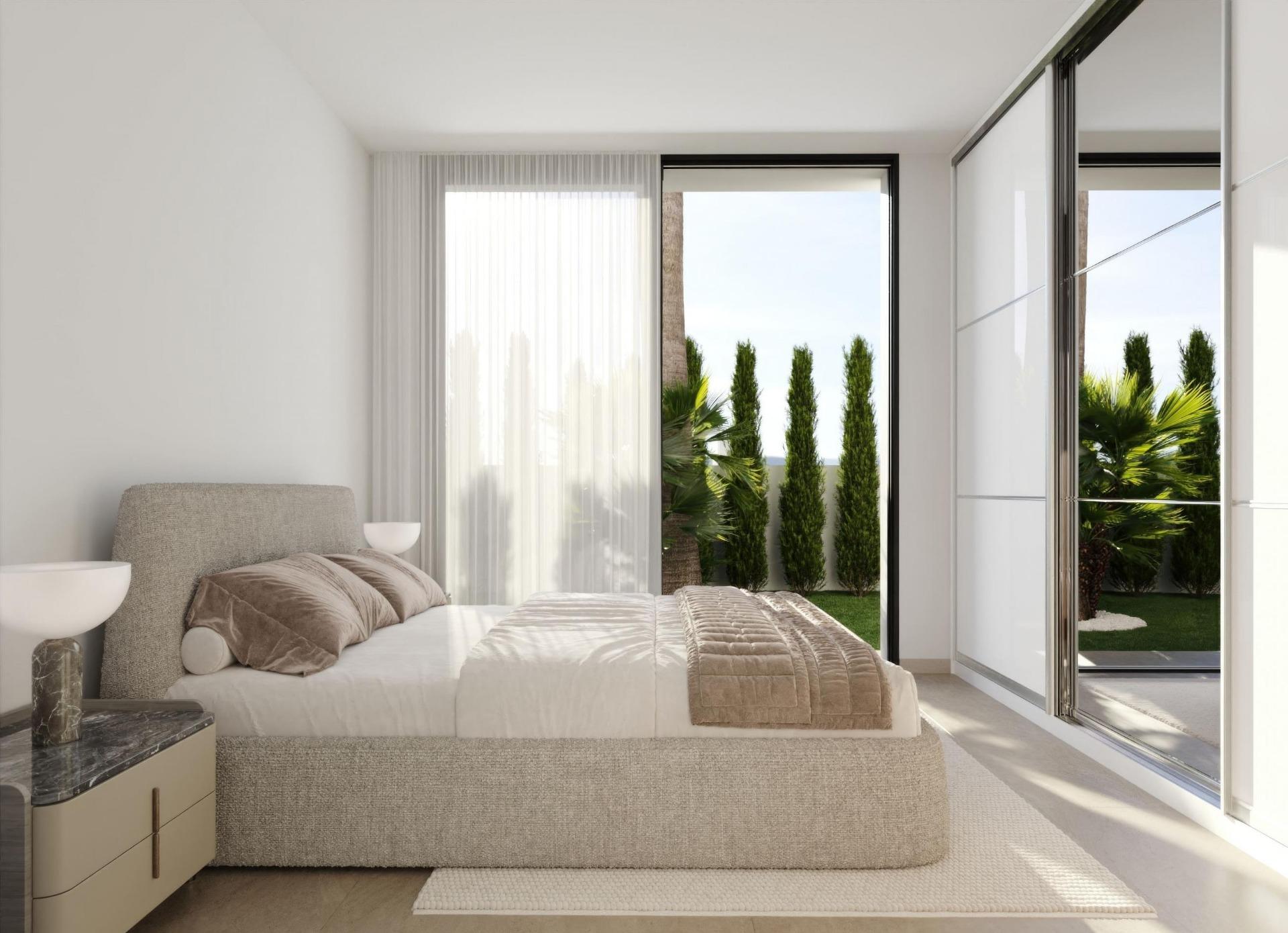 Modern bedroom with beige upholstered bed, neutral bedding, and large glass sliding doors to a garden with tall, slim evergreens.