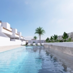 Modern white resort buildings line a rectangular pool with lounge chairs, under a clear blue sky.