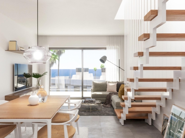 Bright modern living area with a wooden dining table, white chairs, and a gray sofa, lit by a pendant light and large glass doors to outdoors.