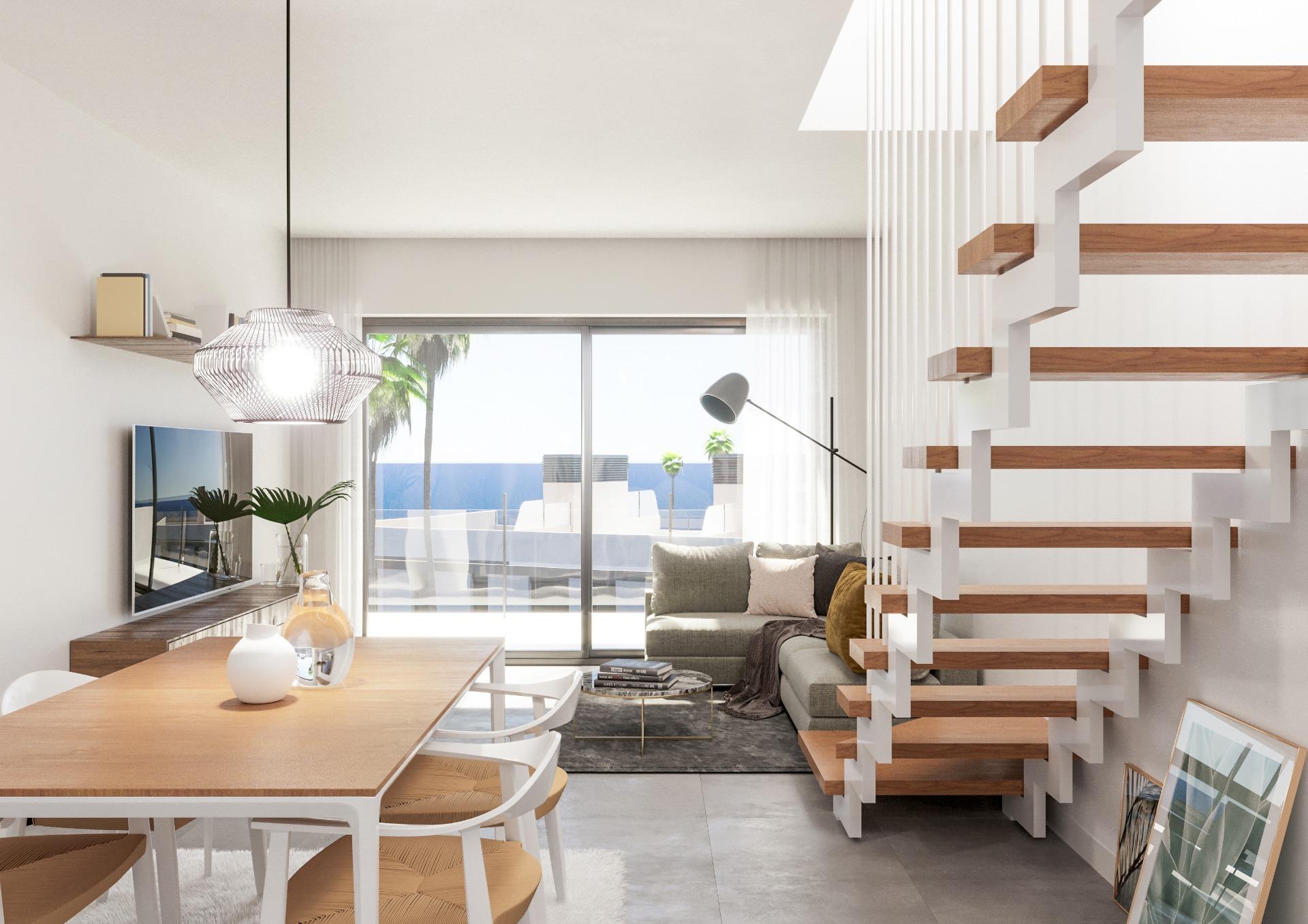 Bright modern living area with a wooden dining table, white chairs, and a gray sofa, lit by a pendant light and large glass doors to outdoors.
