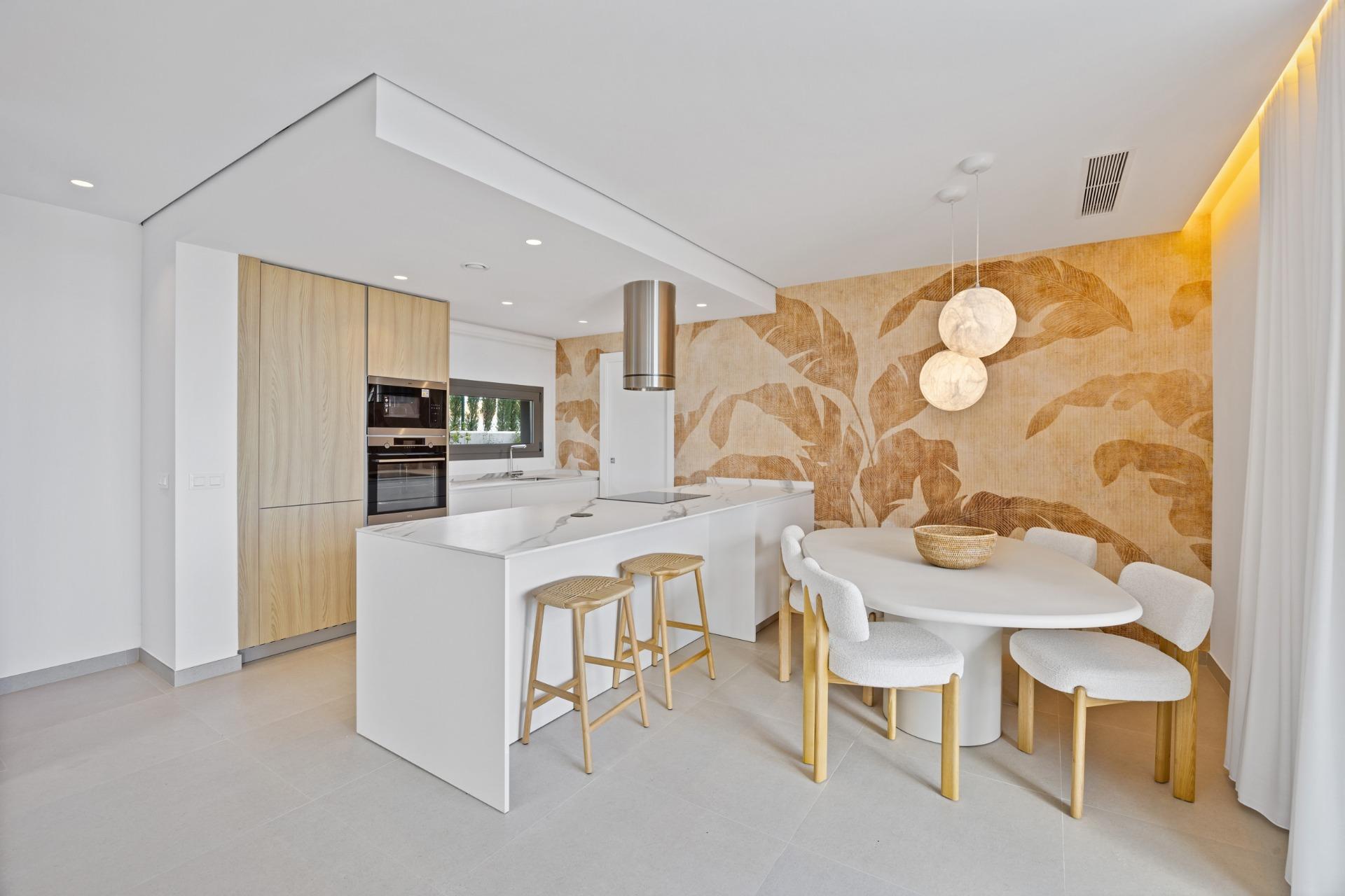 Bright, contemporary kitchen and dining space with a white island, wooden cabinets, and a large leaf-pattern wall mural.