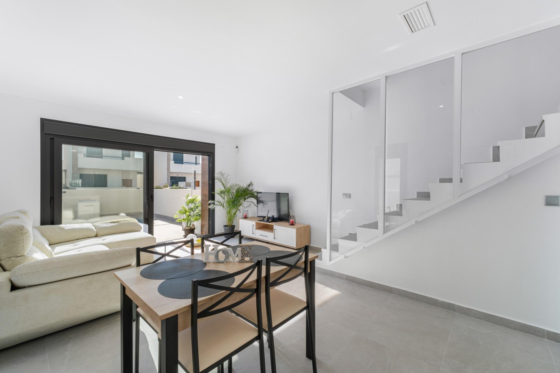 Bright modern living room with a beige sectional, sliding glass doors to a patio, and a dining table nearby.
