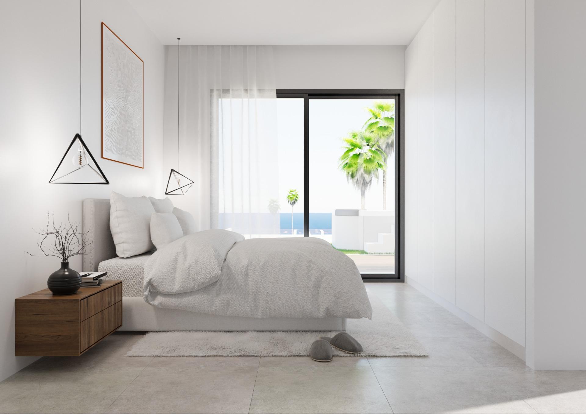 Bright minimalist bedroom with a low white bed, wooden nightstand, and geometric pendant lights, opening to a sunny patio with palm trees through a large glass door.
