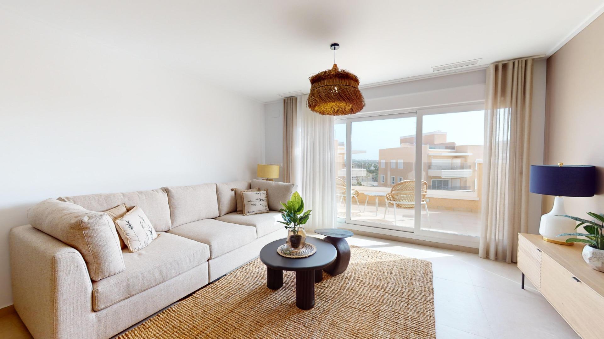 Bright living room with a beige sectional, woven rug, and a large sliding door to a balcony with wicker chairs outside.